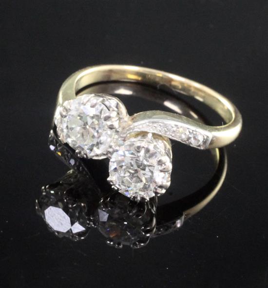 A gold and platinum, two stone diamond cross over ring, with diamond set shoulders, size O.